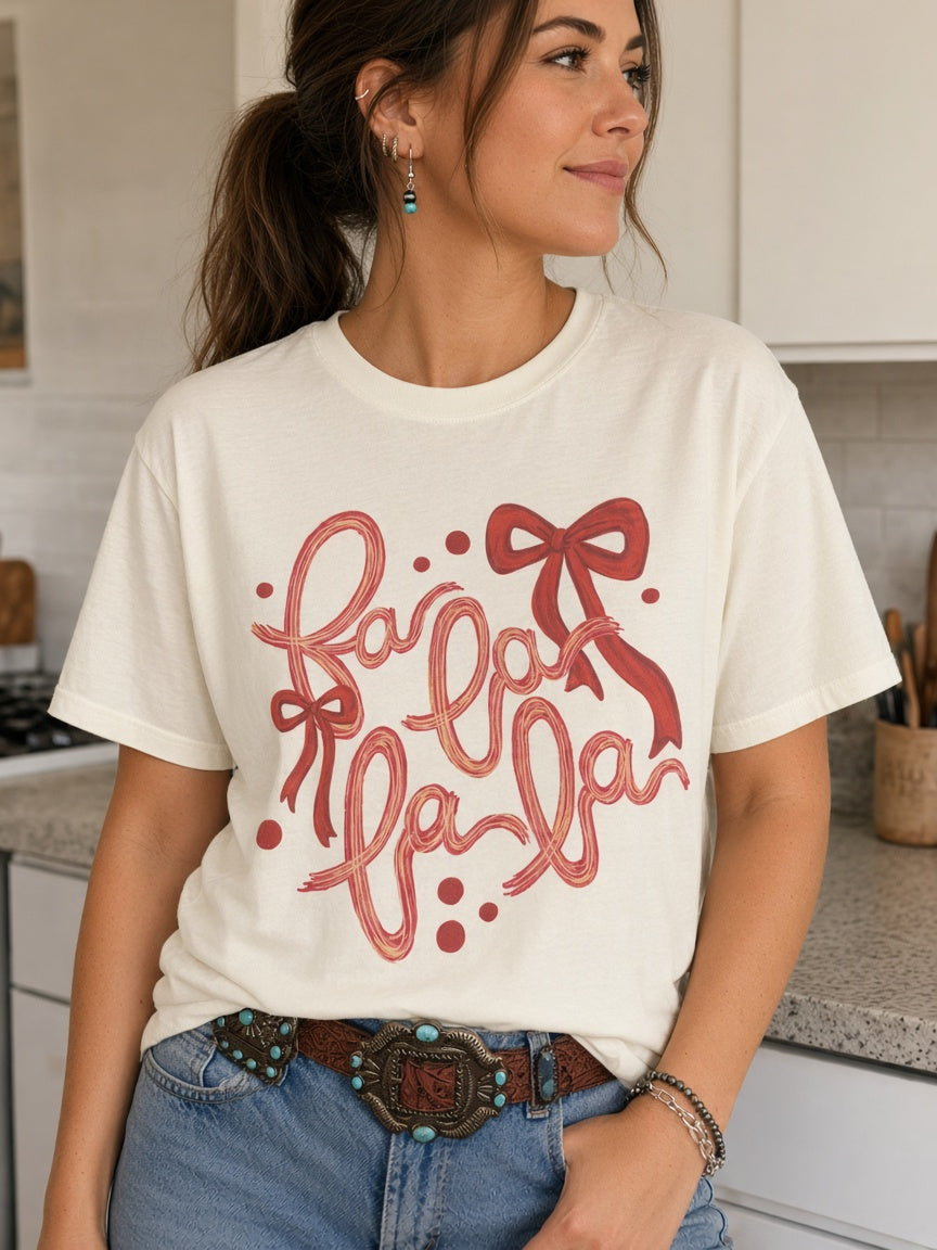 Model wearing Fa La La Christmas Bow Graphic Tee in a kitchen